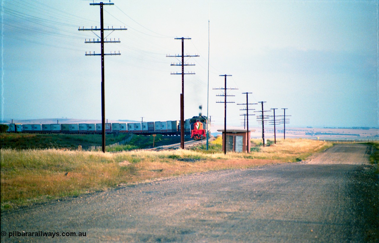 163-02
Bank Box Loop, broad gauge down V/Line Adelaide bound good train rounding the curve on approach behind a third series X class and Australian National BL class, TNT and FCL containers, east end interlocking room and radio mast.
