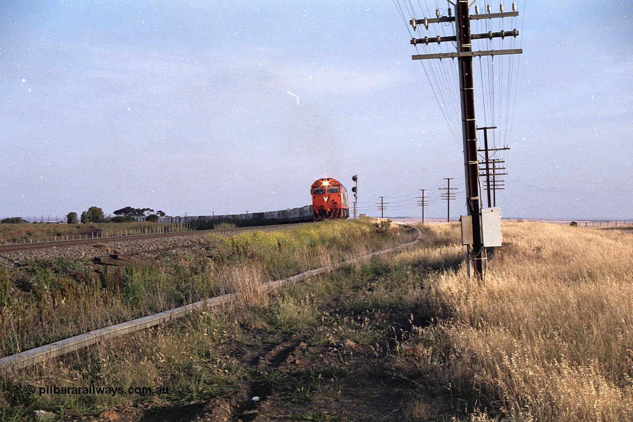 168-03
Bank Box Loop, down V/Line broad gauge goods train to Adelaide behind G class G 540 Clyde Engineering EMD model JT26C-2SS serial 89-1273 and Australian National 700 class 704 AE Goodwin ALCo model DL500G serial G6059-2 round the curve past the down home searchlight signal post.
Keywords: G-class;G540;Clyde-Engineering-Somerton-Victoria;EMD;JT26C-2SS;89-1273;