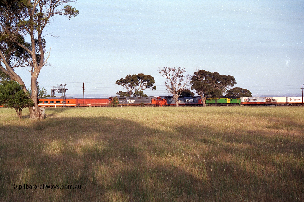 168-06
Bank Box Loop, an up V/Line broad gauge passenger train pulled along by an N class passes a down goods train bound for Adelaide behind G class G 540 Clyde Engineering EMD model JT26C-2SS serial 89-1273 and Australian National 700 class 704 AE Goodwin ALCo model DL500G serial G6059-2 as they stand at the down end of the crossing loop on the mainline.
