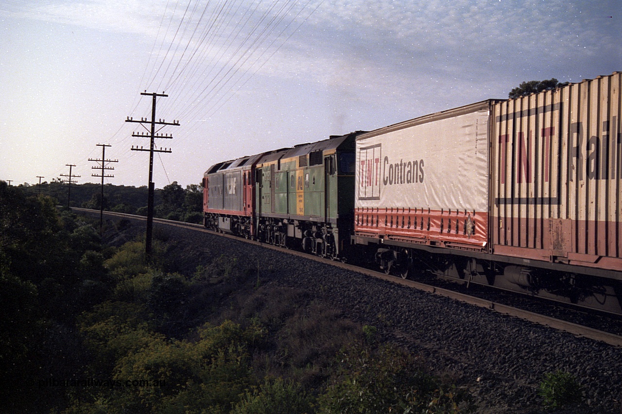 168-10
Bank Box Loop, trailing view of down V/Line broad gauge goods train to Adelaide with G class G 540 Clyde Engineering EMD model JT26C-2SS serial 89-1273 and Australian National 700 class 704 AE Goodwin ALCo model DL500G serial G6059-2 power away from the crossing loop at the Ironbark Road grade crossing.
