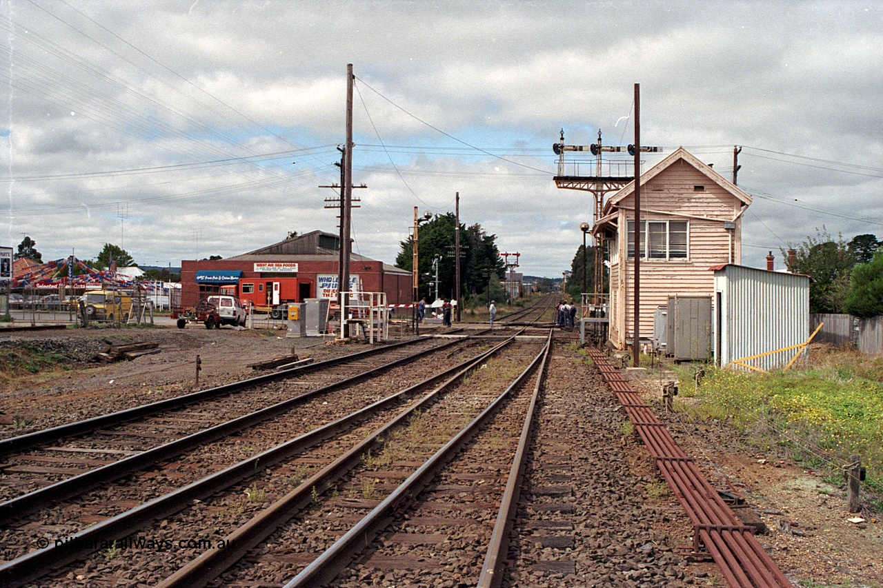 171-04
Ballarat, Linton Junction signal box Gillies St, work site view, interlocked gates being replaced by boom barriers, view of signal box, triple doll semaphore signal Post 20, Timken's Siding disc signal Post 21, staff exchange platform and auto exchange apparatus cover open, track view, point rodding, exchange apparatus gauge leaning against toilet building, standing on Linton line.
