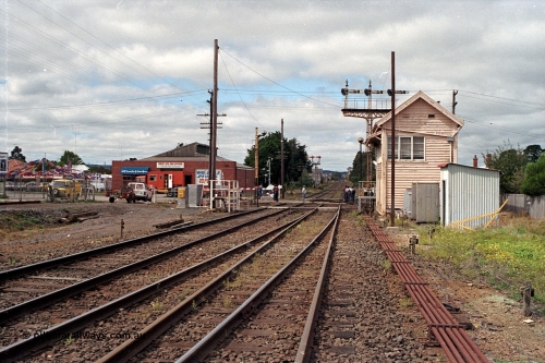 171-04
Ballarat, Linton Junction signal box Gillies St, work site view, interlocked gates being replaced by boom barriers, view of signal box, triple doll semaphore signal Post 20, Timken's Siding disc signal Post 21, staff exchange platform and auto exchange apparatus cover open, track view, point rodding, exchange apparatus gauge leaning against toilet building, standing on Linton line.
