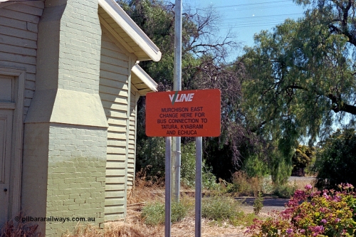 173-14
Murchison East, V/Line station sign, 'Change here for bus connection to...', north end of station building with brick chimney.
