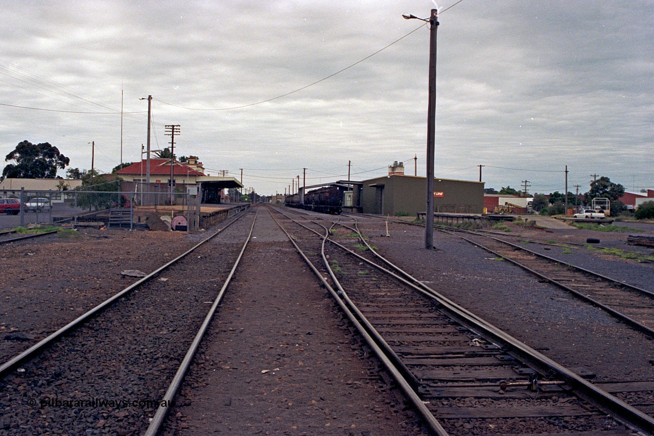 175-05
Shepparton station yard overview looking south, between No.1 and No.2 roads, points to No.3 and 4 roads, stabled fuel train in front of new style goods shed, loading platform, station building and platform on the left.
