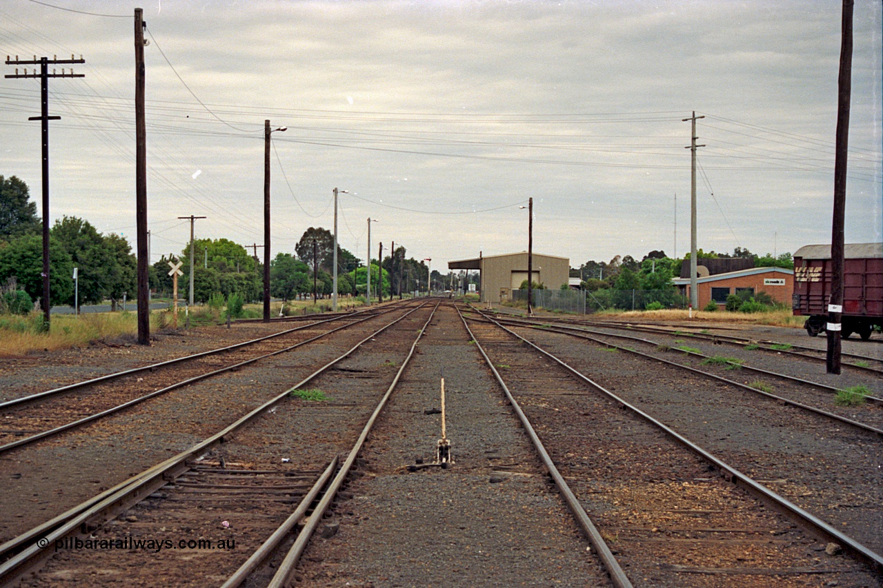 175-08
Shepparton, yard overview looking south, points and lever at bottom are for the crossover to No.1 Rd and the former Car Dock, behind the grade crossing indicator on the right at the former Weighbridge Sidings, up home semaphore signal post in the distance, disused loading facility on the background, goods yard with stabled waggons behind on the right.
