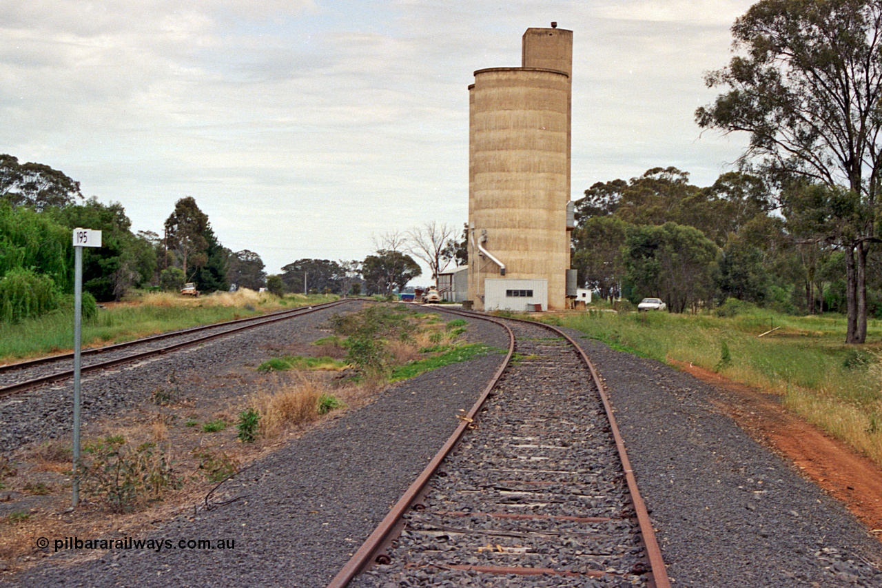 175-20
Pine Lodge, yard overview looking towards Shepparton from the 195 km post, mainline on the left, site of former station and platform on the left, Williamstown style silo complex with super phosphate shed beyond it on the right.
