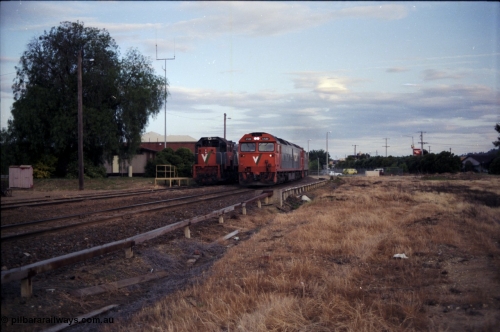 176-22
Wodonga, V/Line standard gauge 'stand-by' loco X class 2nd Series leader X 37 Clyde Engineering EMD model G26C serial 70-700 sits in the Diesel Siding behind the station, as an up Melbourne bound goods train passes behind G class G 520 Clyde Engineering EMD model JT26C-2SS serial 85-1233 and a sister unit, the area to the right is the former broad gauge Cattle Sidings 4 and 5 and the Amoco Siding.
Keywords: G-class;G520;Clyde-Engineering-Rosewater-SA;EMD;JT26C-2SS;85-1233;