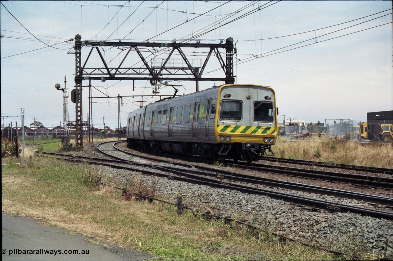 177-12
Newport, track view looking at Geelong - Werribee line, Newport Railway Workshops in the background, an up Werribee 3 car Comeng electric train is rounding the curve in 'The Met' livery.
