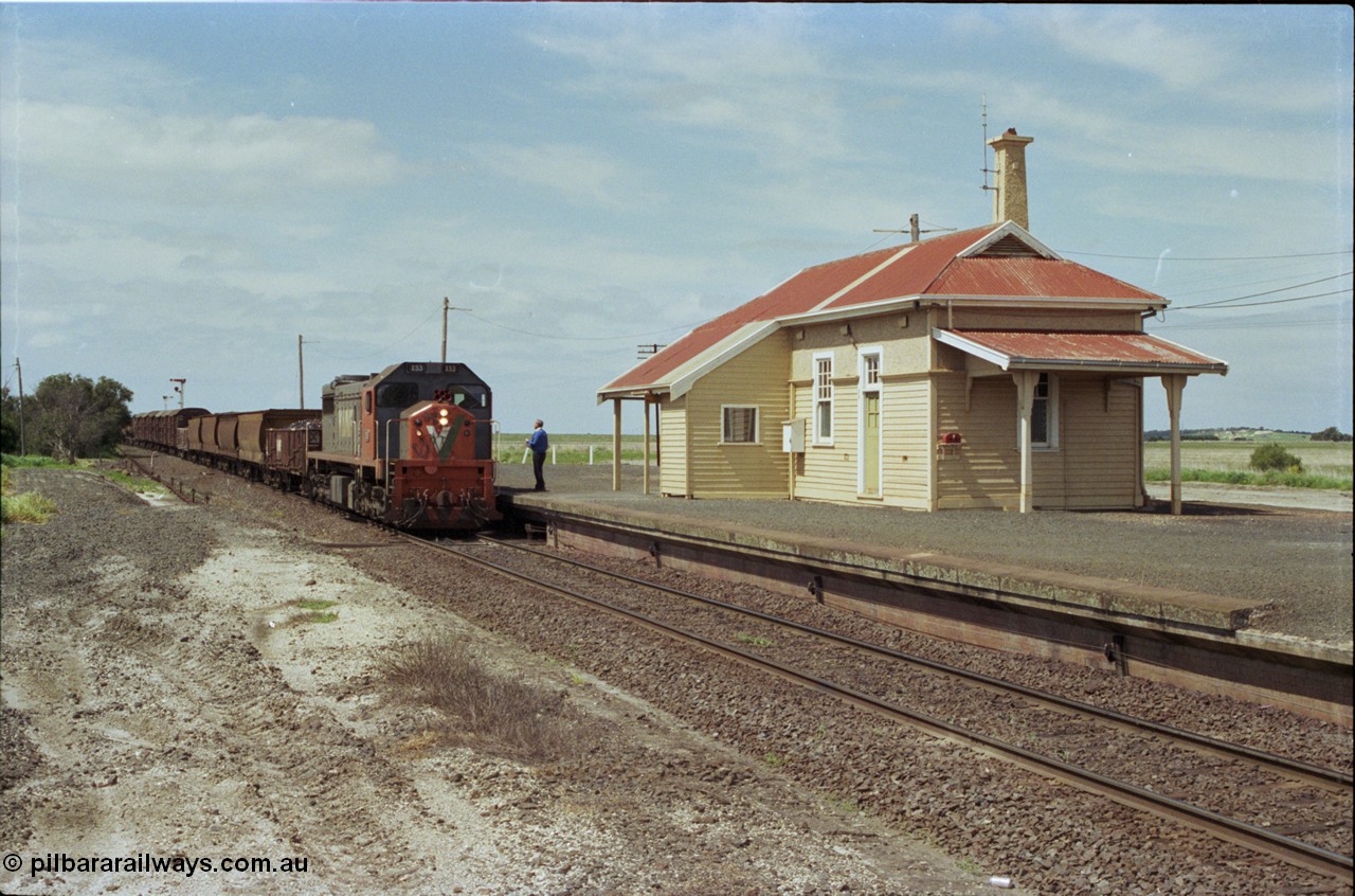 179-02
Gheringhap, station building and platform view with down broad gauge goods train 9153 behind V/Line X class loco X 53 with serial 75-800 a Clyde Engineering Rosewater SA built EMD model G26C, as the signaller readies to swap the electric staff from North Geelong C Box for a train order to Maroona.
Keywords: X-class;X53;Clyde-Engineering-Rosewater-SA;EMD;G26C;75-800;