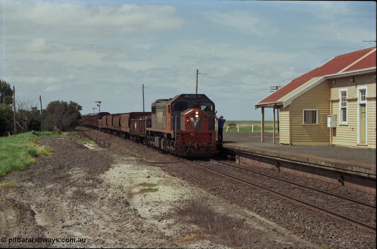 179-03
Gheringhap, station building and platform view with down broad gauge goods train 9153 behind V/Line X class loco X 53 with serial 75-800 a Clyde Engineering Rosewater SA built EMD model G26C, as the signaller swaps the electric staff from North Geelong C Box for a train order to Maroona.
Keywords: X-class;X53;Clyde-Engineering-Rosewater-SA;EMD;G26C;75-800;