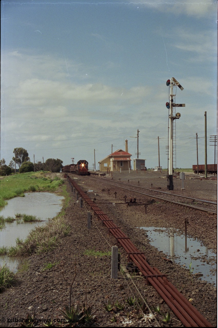 179-04
Gheringhap, yard overview looking east, broad gauge V/Line down goods train 9153 departs for Maroona with the signal on post 4 pulled off for the Maroona line, point rodding and interlocking is spaced away from the line as this location used to have double mainlines, on the right are gypsum waggons in Sidings B.
Keywords: X-class;X53;Clyde-Engineering-Rosewater-SA;EMD;G26C;75-800;