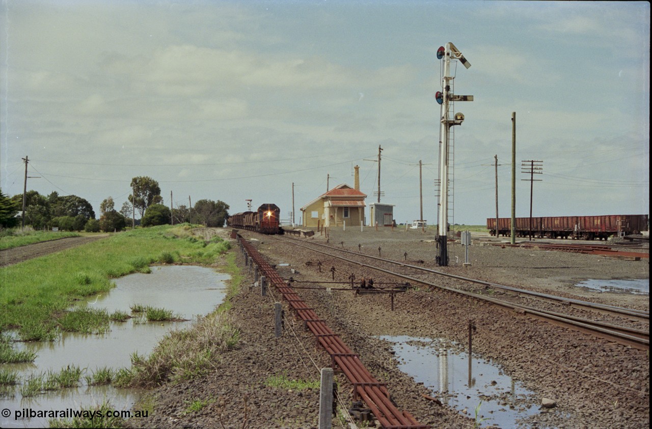 179-05
Gheringhap, yard overview looking east, broad gauge V/Line down goods train 9153 departs for Maroona with the signal on post 4 pulled off for the Maroona line, point rodding and interlocking is spaced away from the line as this location used to have double mainlines, on the right are gypsum waggons in Sidings B.
Keywords: X-class;X53;Clyde-Engineering-Rosewater-SA;EMD;G26C;75-800;