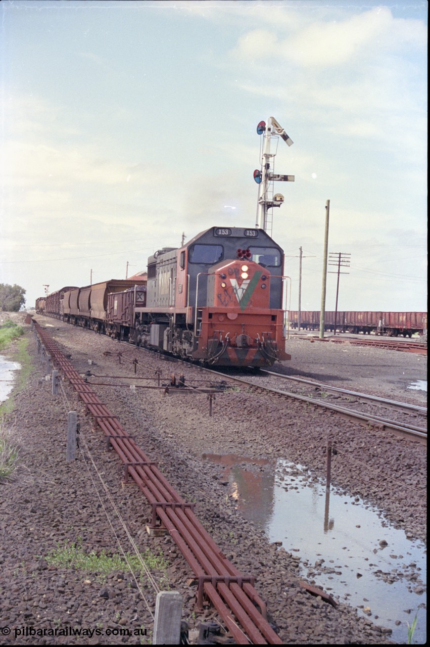 179-06
Gheringhap, yard overview looking east, broad gauge V/Line down goods train 9153 departs for Maroona with the signal on post 4 pulled off and the points are set for the Maroona line, point rodding and interlocking is spaced away from the line as this location used to have double mainlines, on the right are gypsum waggons in Sidings B.
Keywords: X-class;X53;Clyde-Engineering-Rosewater-SA;EMD;G26C;75-800;