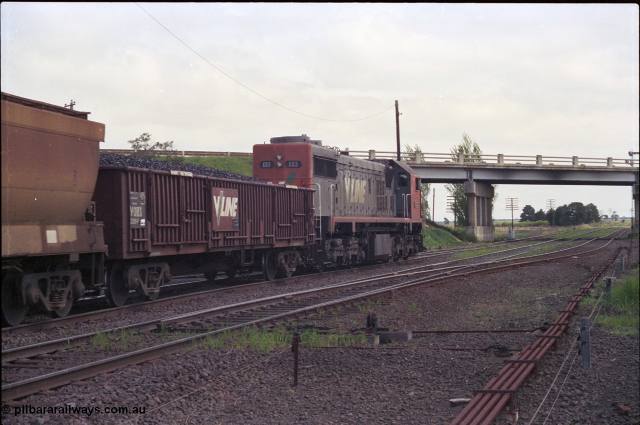 179-07
Gheringhap, track view looking west, broad gauge V/Line down goods train 9153 is bound for Maroona and beyond, the other lines are the Ballarat Line in the middle and Siding C on the right running under the Midland Highway overpass, point rodding and interlocking for Siding C points are visible, Siding C used to form part of the original up line back in double track days.
Keywords: X-class;X53;Clyde-Engineering-Rosewater-SA;EMD;G26C;75-800;