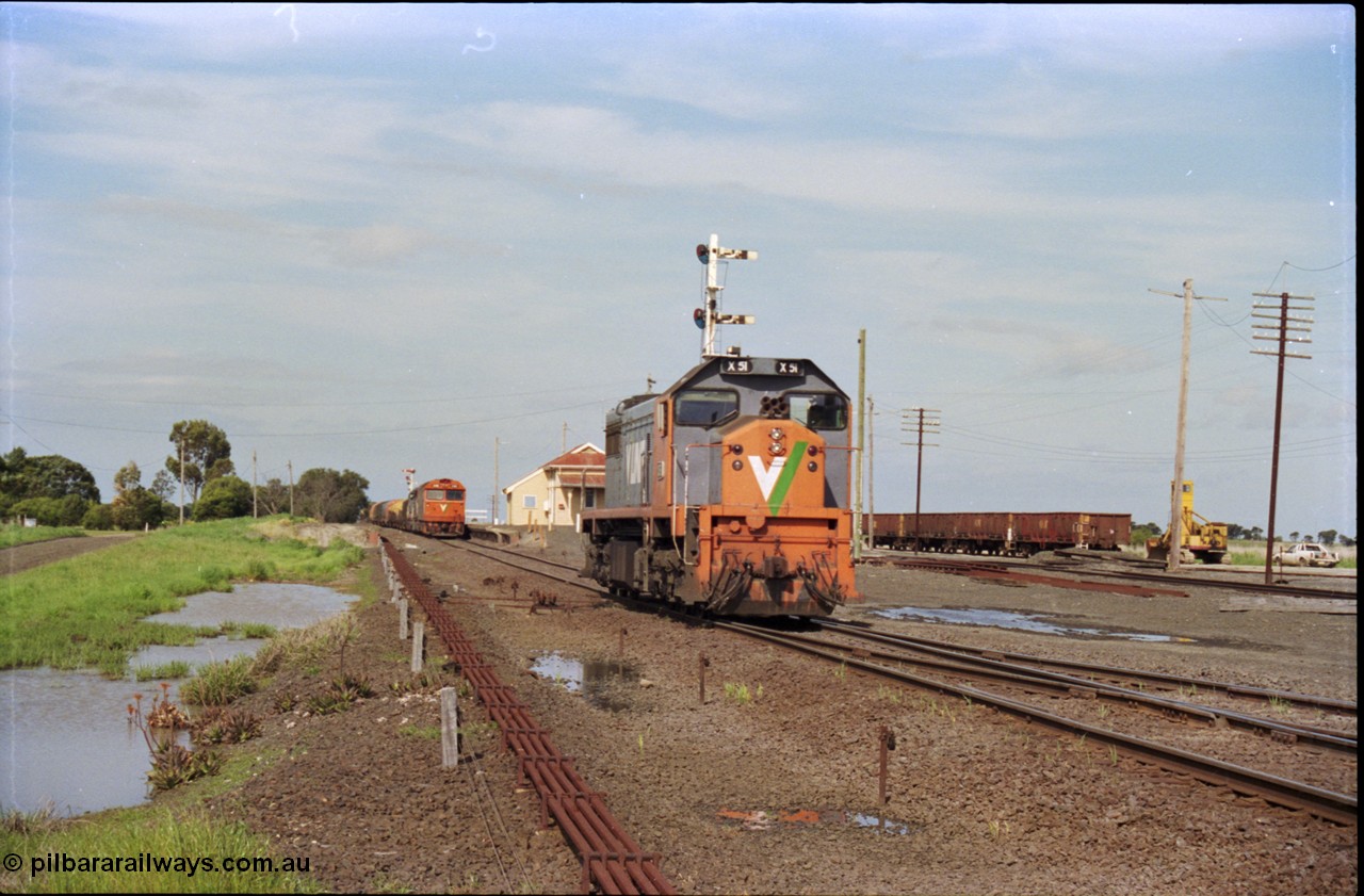 179-16
Gheringhap, V/Line broad gauge X class locomotive X 51 Clyde Engineering EMD model G26C serial 75-798 has been removed from train 9169 and is running light engine to stable in Siding C, the disc for Siding C on signal post 4 can just be made out above the loco's cab, 9169 holds the mainline at the station and a rake of gypsum waggons sits in Sidings B on the right.
Keywords: X-class;X51;Clyde-Engineering-Rosewater-SA;EMD;G26C;75-798;