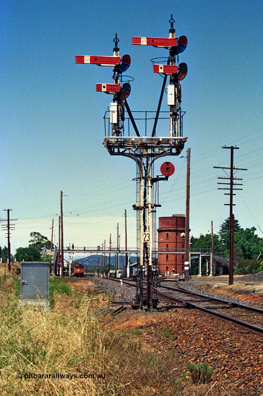 180-08
Wangaratta, yard view looking south past the up home semaphore signal post No.23 with the down V/Line broad gauge Albury passenger train conducting platform duties.
