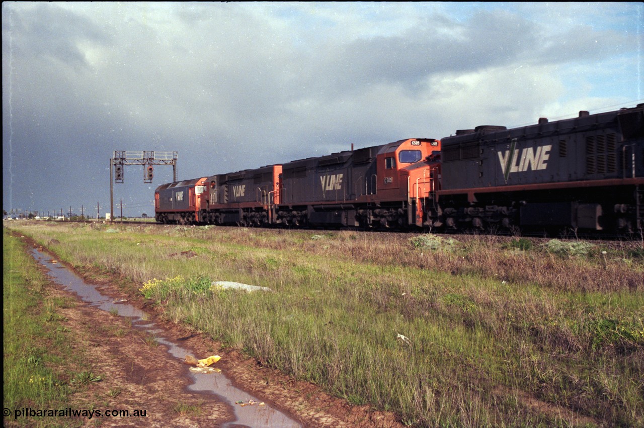 183-03
Deer Park West, an up broad gauge V/Line goods train behind the quad lash up of a G class, 2 C classes and an X class as they pass under signal gantry with searchlight signals 1/10 and 1/22 on the North Line.
