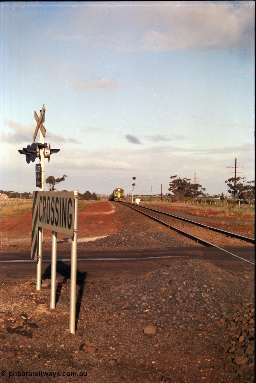 183-04
Rockbank, an Adelaide bound down broad gauge goods train behind Australian National BL class BL 31 Clyde Engineering EMD model JT26C-2SS serial 83-1015 and 700 class 705 AE Goodwin ALCo model DL500G serial G6059-3 climbs the grade as it approaches the grade crossing for Station Road.
