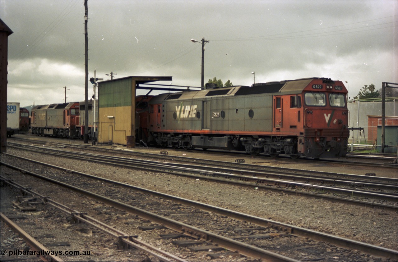 184-01
Albury loco depot fuel point, V/Line standard gauge locos lined up awaiting the Sunday run of goods trains back to Melbourne, G class G 527 Clyde Engineering EMD model JT26C-2SS serial 88-1257, C class C 503 Clyde Engineering EMD model GT26C serial 76-826 and G classes G 520 serial 85-1233 and partly obscured G 525 serial 86-1238, semaphore signal and rear of fuel point, view across yard, point rodding.
Keywords: G-class;G527;Clyde-Engineering-Somerton-Victoria;EMD;JT26C-2SS;88-1257;C-class;C503;GT26C;76-826;G520;85-1233;G525;86-1238;