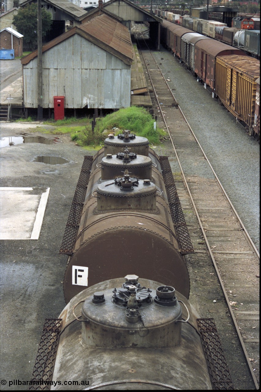 184-05
Albury station yard, broad gauge road on the west side of the yard, through standard gauge running lines on the right, roof detail of V/Line VTQF type bogie fuel tank waggons VTQF 120 and VTQF 122, goods shed behind, standard gauge track on right, on the left it used to have a broad gauge connection. Both waggons built new at Newport Workshops as OT type tank waggons in May and March 1929, both to TWF in October 1961, then 120 recoded to VTQY in September 1979 and 122 to VTQY in April 1980, then in 1987/88 VTQY were recoded to VTQF.
Keywords: VTQF-type;VTQF120;VTQF122;TWF-type;Victorian-Railways-Newport-WS;OT-type;