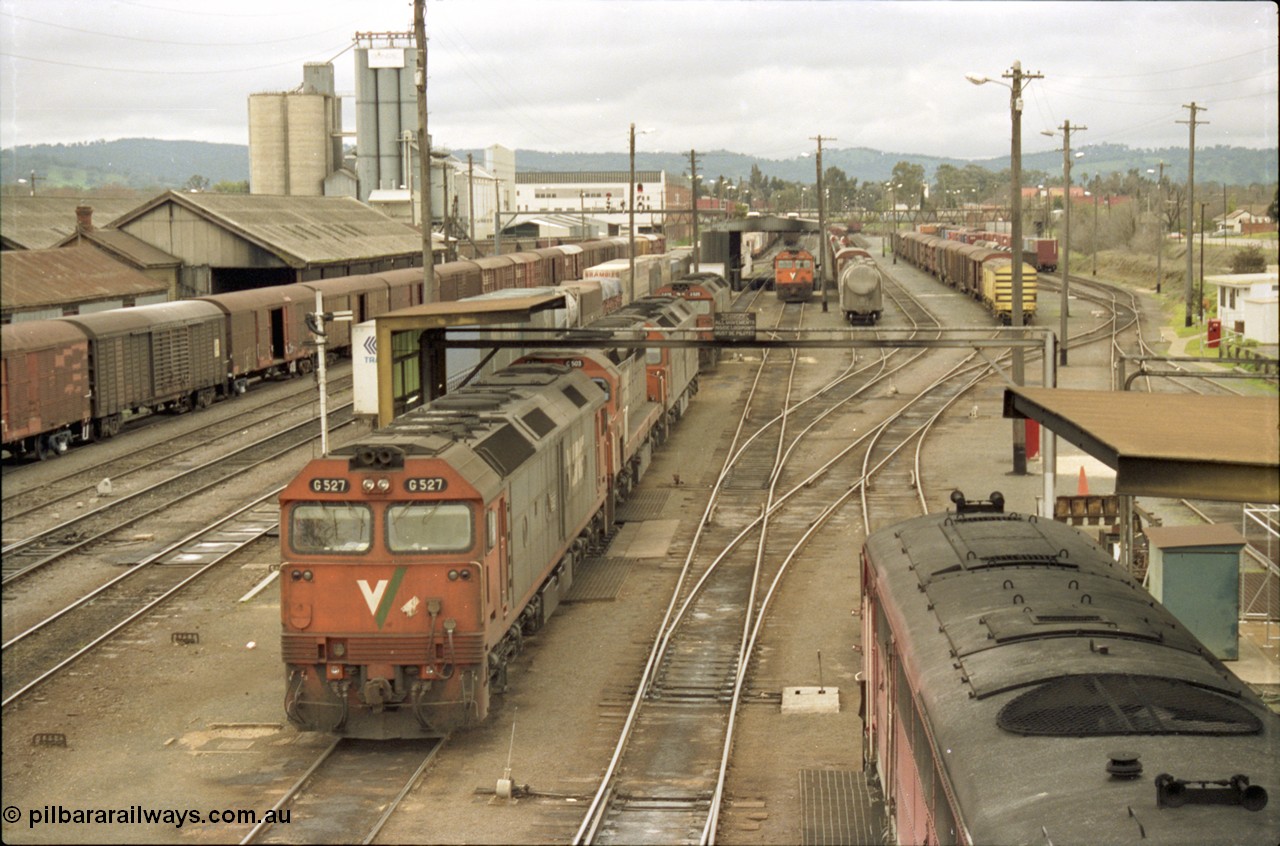 184-08
Albury station yard and loco depot fuel point overview looking north, V/Line standard gauge locos lined up awaiting the Sunday run of goods trains back to Melbourne, G class G 527 Clyde Engineering EMD model JT26C-2SS serial 88-1257, C class C 503 Clyde Engineering EMD model GT26C serial 76-826 and G class units G 520 serial 85-1233, G 525 serial 86-1238 and G 523 serial 86-1236, goods shed at left behind louvre vans, the stabled train beside the locos is SM5, elevated view.
Keywords: G-class;G527;Clyde-Engineering-Somerton-Victoria;EMD;JT26C-2SS;88-1257;C-class;C503;GT26C;76-826;G520;85-1233;G525;86-1238;G523;86-1236;