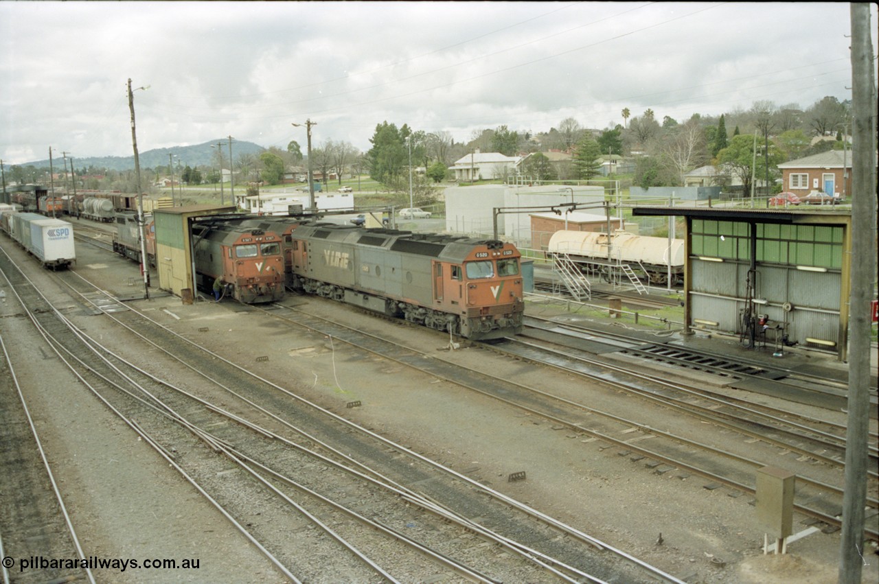 184-21
Albury station yard overview, loco depot, V/Line standard gauge G class G 527 Clyde Engineering EMD model JT26C-2SS serial 88-1257 takes on water at the fuel point with C class behind it while G class G 520 serial 85-1233 leading sister G 525 serial 86-1238 shunts past light engine, elevated view of logo depot and fuel points.
Keywords: G-class;G527;Clyde-Engineering-Somerton-Victoria;EMD;JT26C-2SS;88-1257;C-class;G520;85-1233;G525;86-1238;