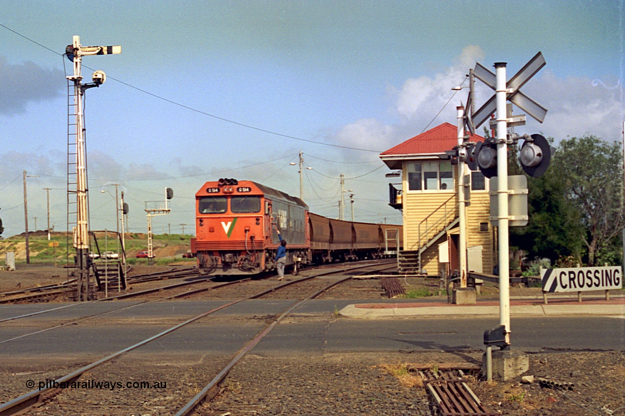 185-06
North Geelong C Box looking across the Separation Street grade crossing as a V/Line G class locomotive G 514 Clyde Engineering EMD model JT26C-2SS serial 85-1242 departs North Geelong Yard with 9121 empty grain train, the driver has just collected the Gheringhap electric staff off the signaller, the tracks to the grain loop and the Loop Line to Melbourne are curving around to the left beyond the mechanical and electric signal posts.
Keywords: G-class;G514;Clyde-Engineering-Rosewater-SA;EMD;JT26C-2SS;85-1242;