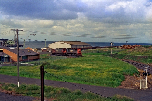 185-09
North Geelong Grain Loop view from Corio Quay Road across to Corio Quay with Access Road and grade crossing, and the former tracks to South Quay visible at the left corner, the grain train is approaching the Home Signal that protected the former Freezing Works Siding.
