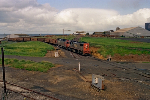 185-11
North Geelong Grain Loop view from Corio Quay Road across Access Road grade crossing with the tracks to Corio Quay at the very bottom of image, as the grain train behind V/Line locos X class locomotive X 41 Clyde Engineering EMD model G26C serial 70-704 long end leading and G class locomotive G 528 Clyde Engineering EMD model JT26C-2SS serial 88-1258 having past the Home Signal and crossing the former tracks for the Freezing Works Sidings.
Keywords: X-class;X41;Clyde-Engineering-Granville-NSW;EMD;G26C;70-704;