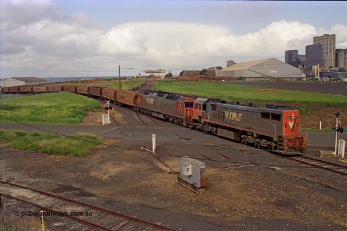 185-12
North Geelong Grain Loop view from Corio Quay Road across Access Road grade crossing with the tracks to Corio Quay at the very bottom of image, as the grain train behind V/Line locos X class locomotive X 41 Clyde Engineering EMD model G26C serial 70-704 long end leading and G class locomotive G 528 Clyde Engineering EMD model JT26C-2SS serial 88-1258 having past the Home Signal and crossing the former tracks for the Freezing Works Sidings.
Keywords: X-class;X41;Clyde-Engineering-Granville-NSW;EMD;G26C;70-704;