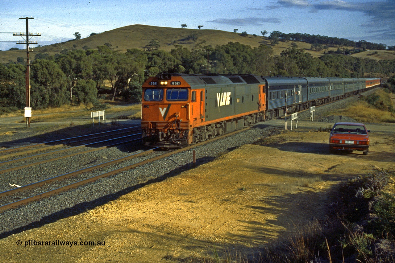 191-02
Wandong, Road grade crossing, near former Mathiesons Siding, UP Melbourne Express behind standard early 1990s V/Line G class power of Clyde Engineering built EMD model JT26C-2SS, G 521 serial 85-1234.
Keywords: G-class;G521;Clyde-Engineering-Rosewater-SA;EMD;JT26C-2SS;85-1234;