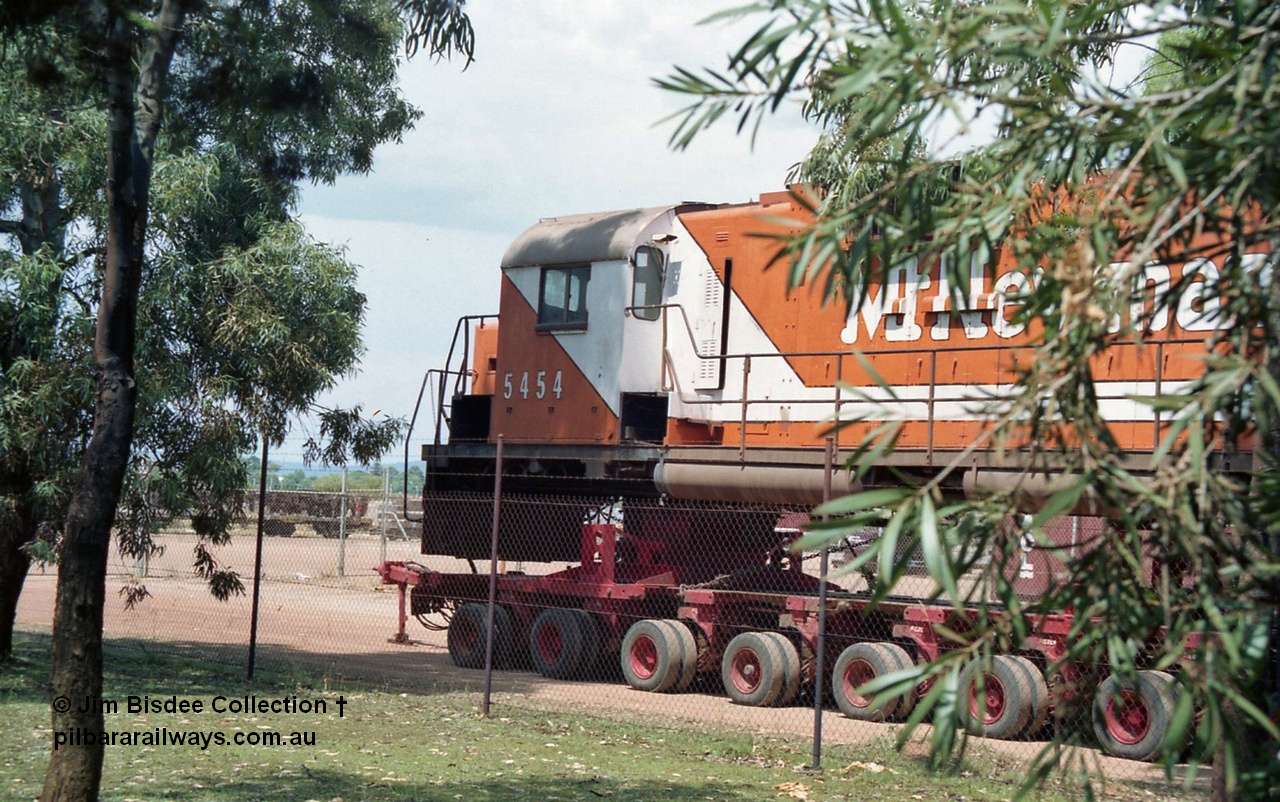 20861
Bassendean, Goninan workshops, sitting outside the locked gates having just been bought down from Port Hedland, Mt Newman Mining's AE Goodwin ALCo C636 unit 5454 serial G6012-3 on a ninety six wheel road float. 5454 will be rebuilt into CM40-8M unit 5641 by June 1992. Image taken January 1992.
Jim Bisdee photo.
Keywords: 5454;AE-Goodwin;ALCo;C636;G6012-3;