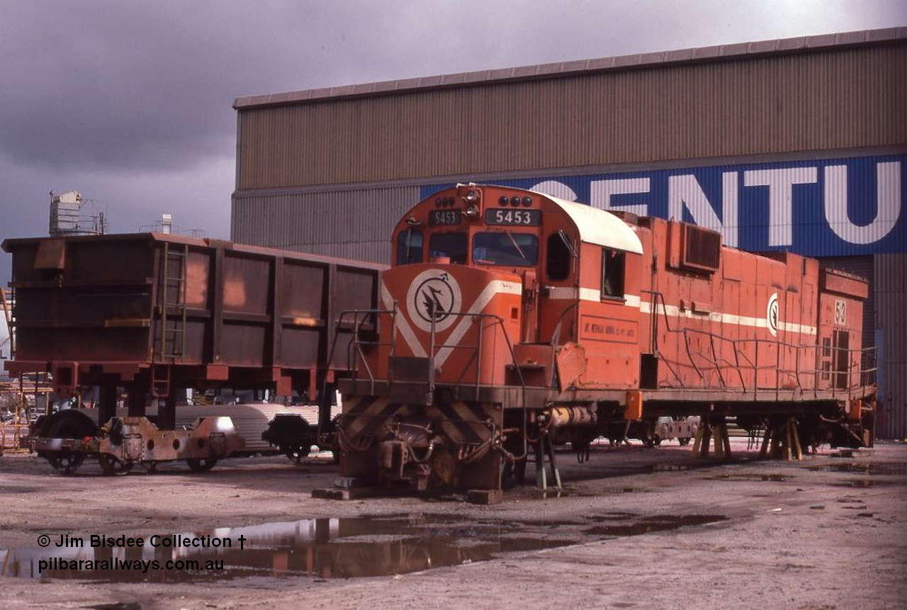 5945 001 Welshpool 1987April
Welshpool, Goninan workshops, Mt Newman Mining C636 ALCo unit 5453 serial G6012-2 built by AE Goodwin in 1969 is undergoing a world first as it gets rebuilt into a GE C36-7M locomotive. In this April 1987 view the process has started with the bogies and fuel tank removed. By February 1988 it would be the final C36-7M built for Mt Newman Mining as 5513. April 1987.
Jim Bisdee photo.
Keywords: 5453;AE-Goodwin;ALCo;C636;G6012-2;