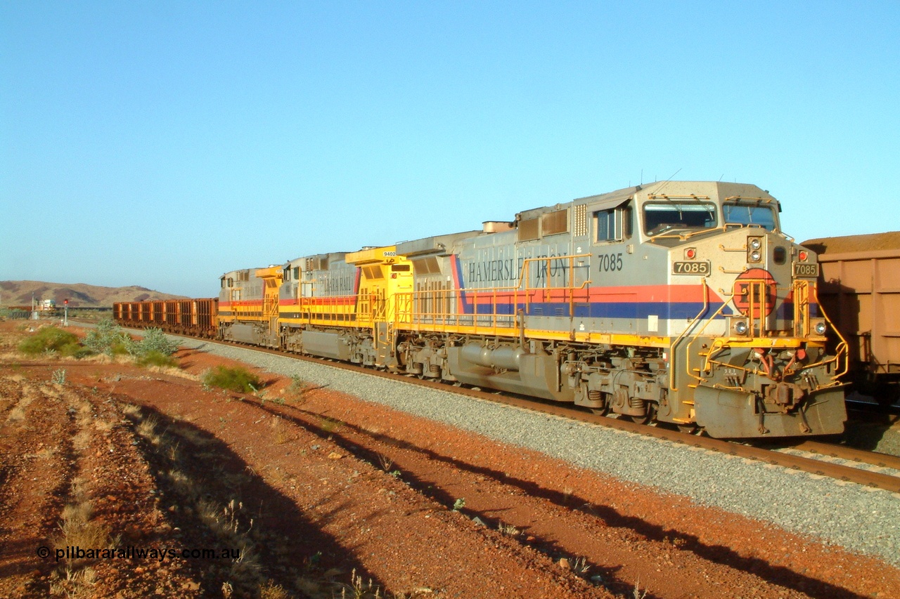 050110 175658r
Harding Siding, 42 km on the Cape Lambert line, following a hot box alarm an empty Deepdale bound train headed by triple General Electric built Dash 9-44CW units 7085 serial 47764 in owner's Hamersley Iron livery, 9402 serial 53456 in Robe River Pilbara Rail livery and 7061 serial 54768 in Hamersley Iron Pilbara Iron livery have cut off and pulled into the siding with eight waggons of the consist. The locos of the loaded train 7069 and 7077 can just be seen to the left of the signal are cutting off the defect waggons. The loaded train is stabled on the mainline track. Monday 10th January 2005.
Keywords: 7085;GE;Dash-9-44CW;47764;